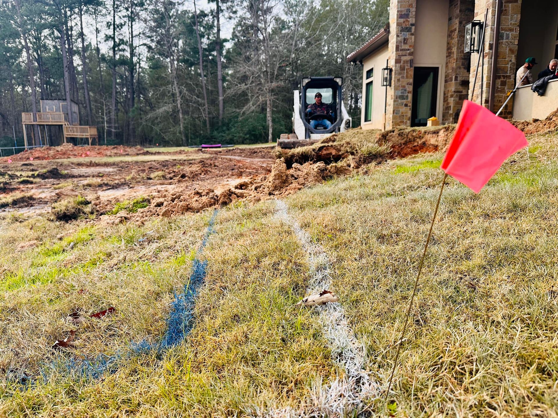A construction site with a bulldozer and a red flag in the foreground.