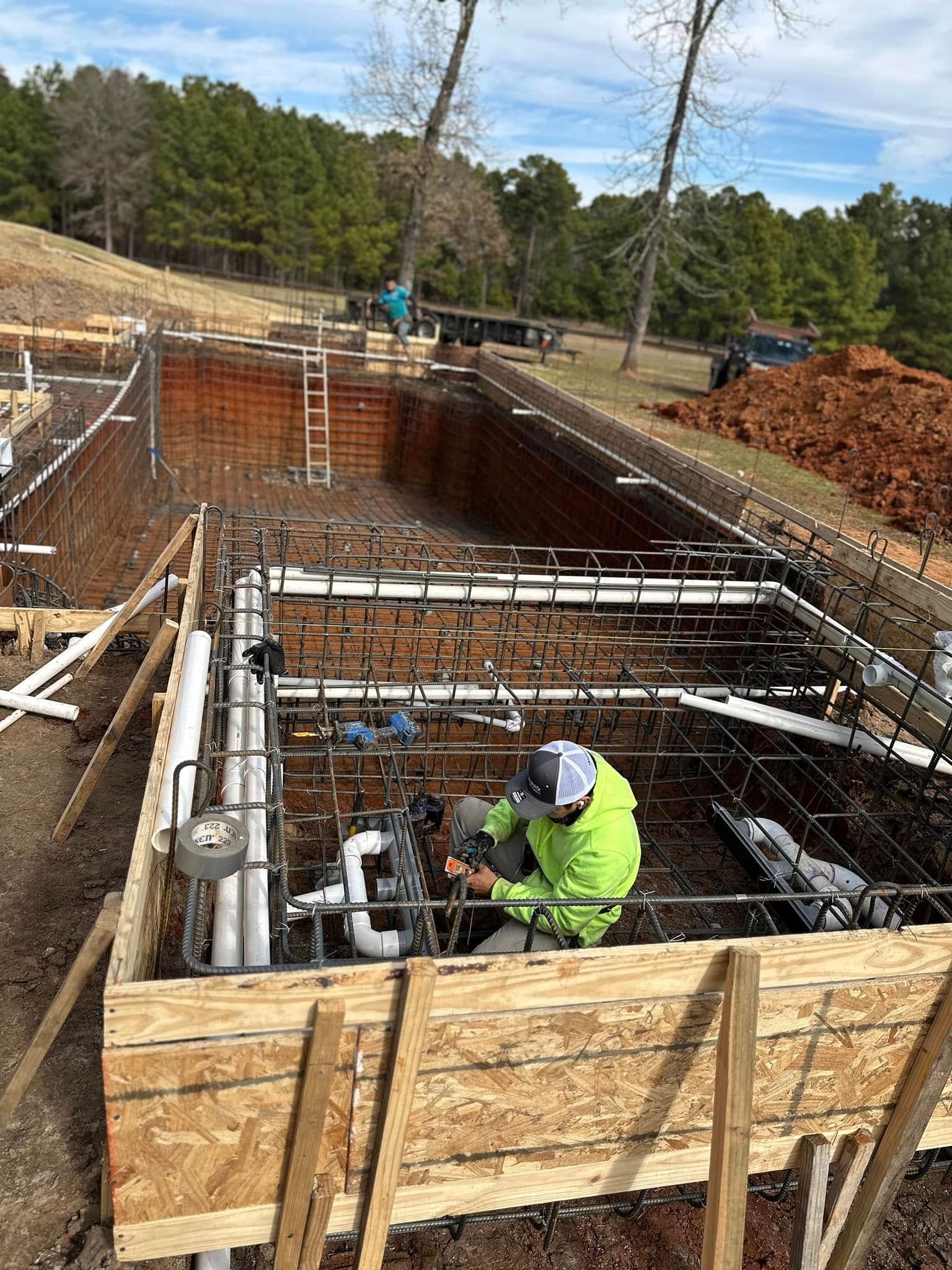 A man is working on a swimming pool under construction.