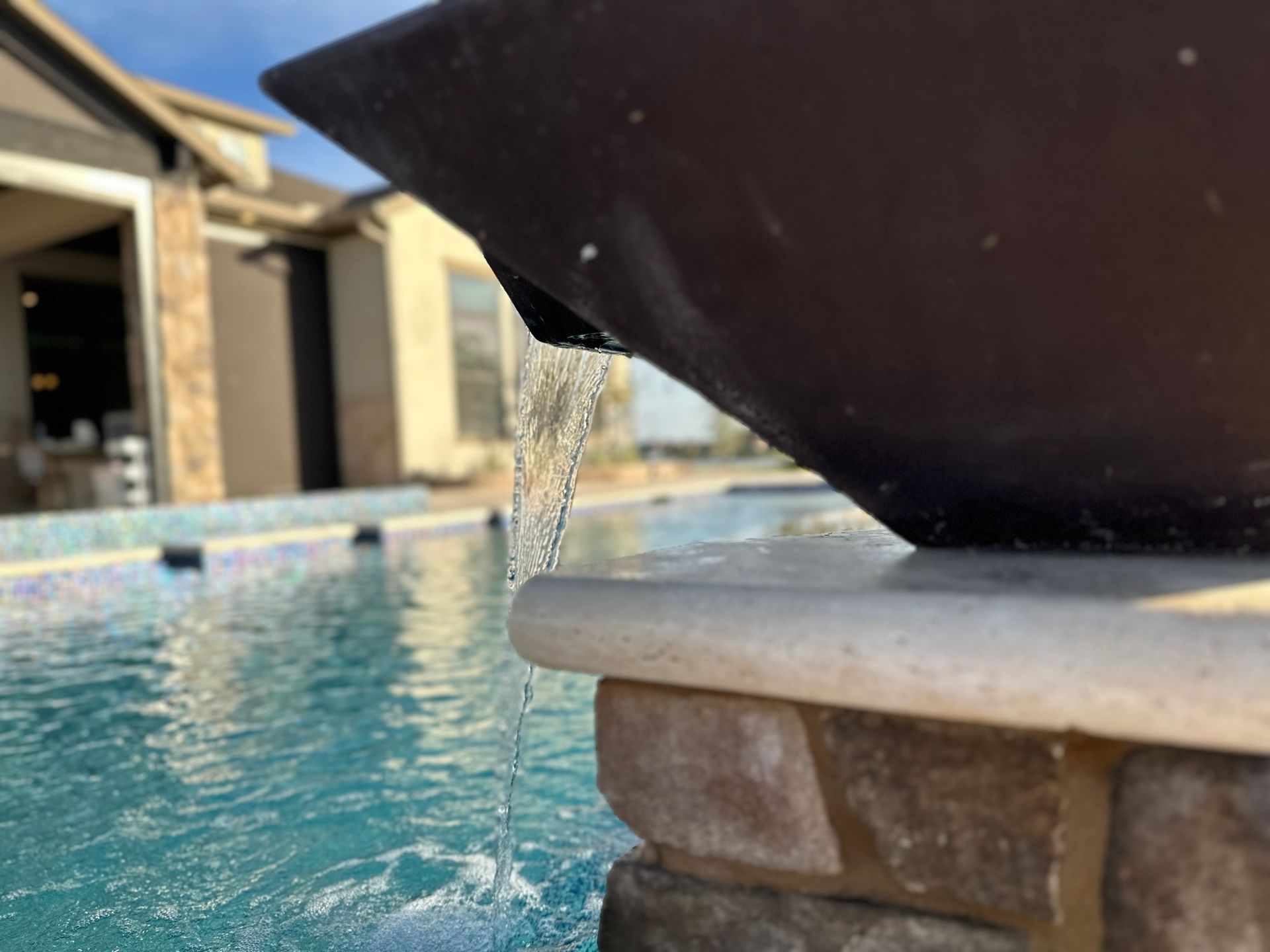 A fountain is pouring water into a swimming pool.
