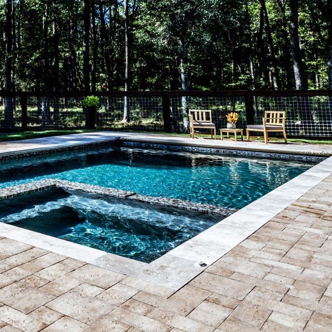 A large swimming pool surrounded by chairs and a fence