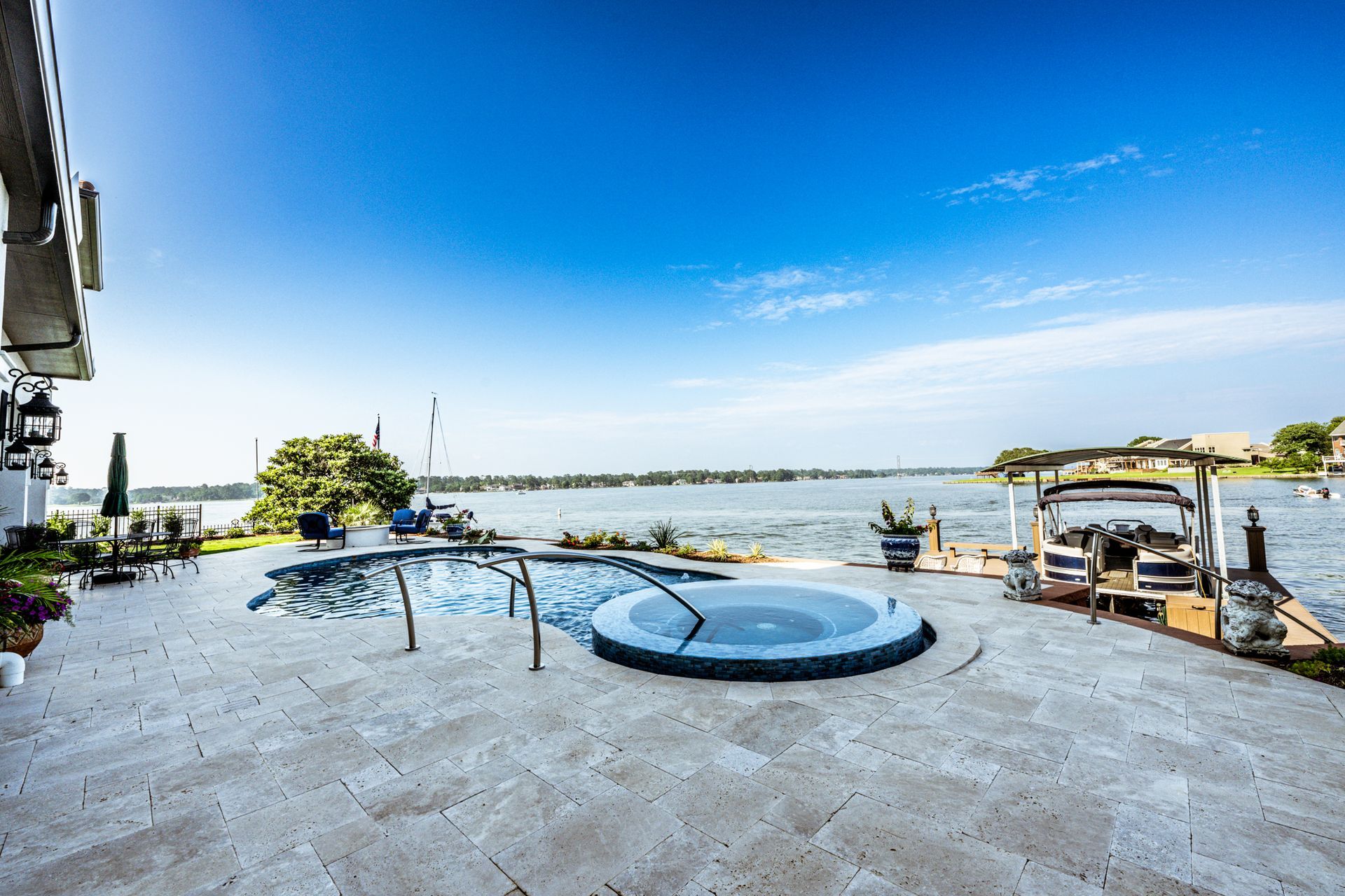 A large swimming pool with a hot tub next to a body of water.