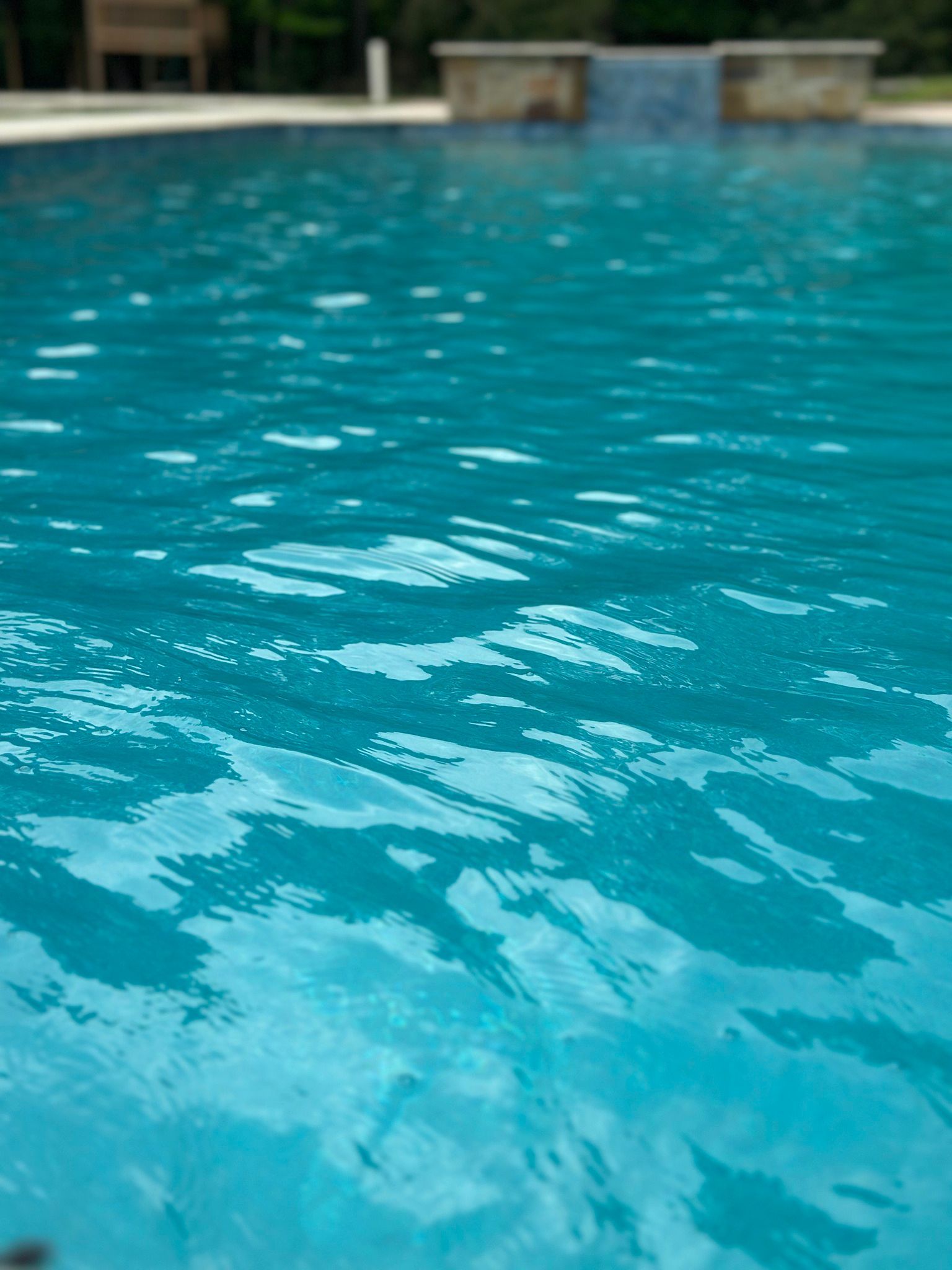 A large swimming pool filled with blue water and a waterfall in the background.