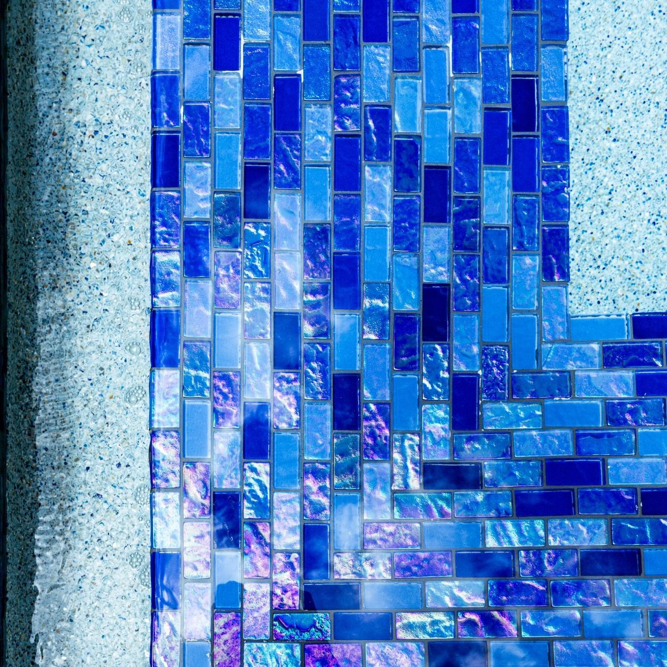 A close up of a blue mosaic tile wall in a pool.