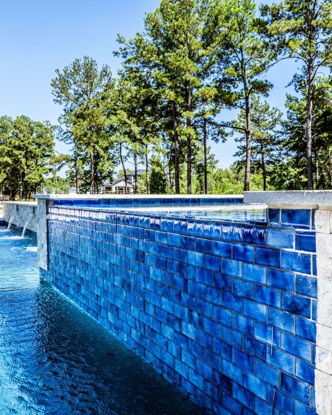 A swimming pool with blue tiles and trees in the background