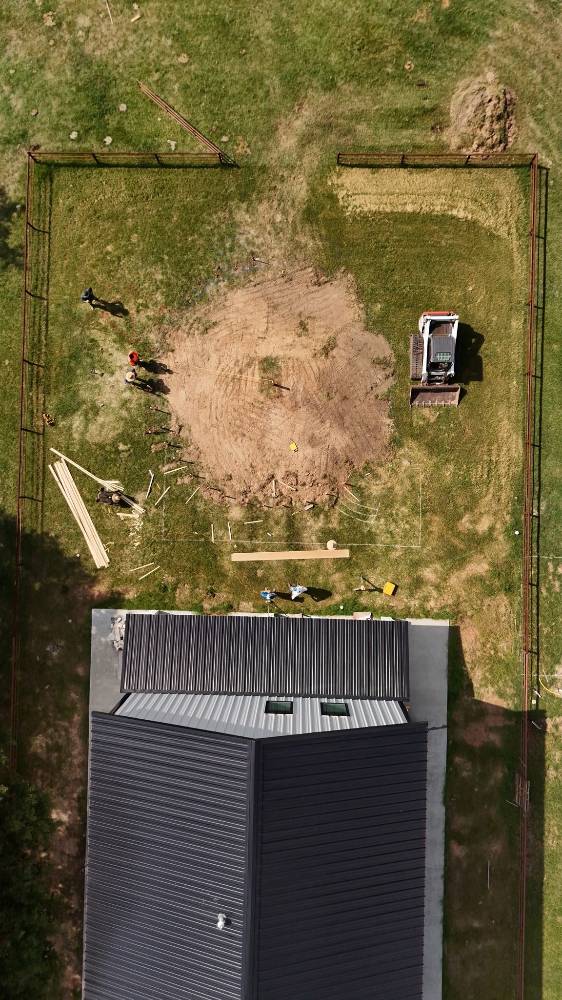 An aerial view of a house being built on a lush green field.