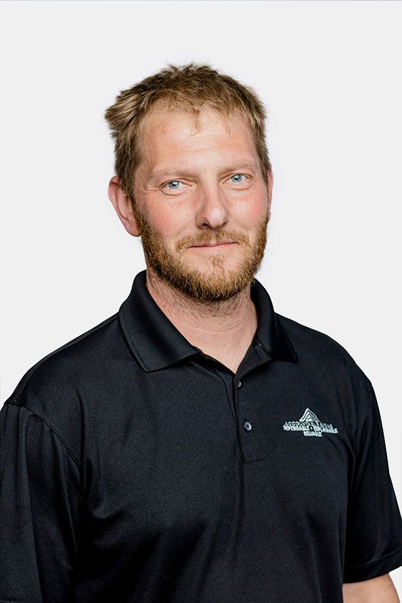 A man with a beard is wearing a black polo shirt.