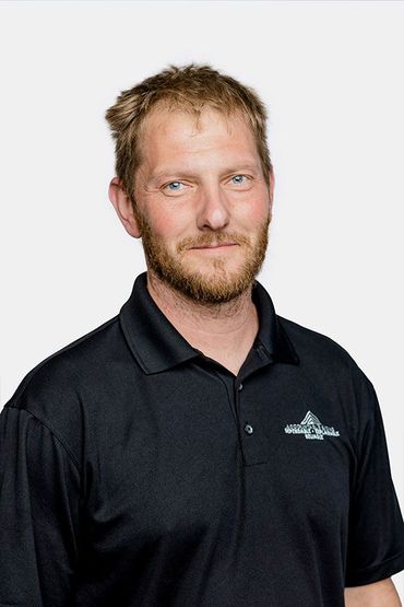 A man with a beard is wearing a black polo shirt.