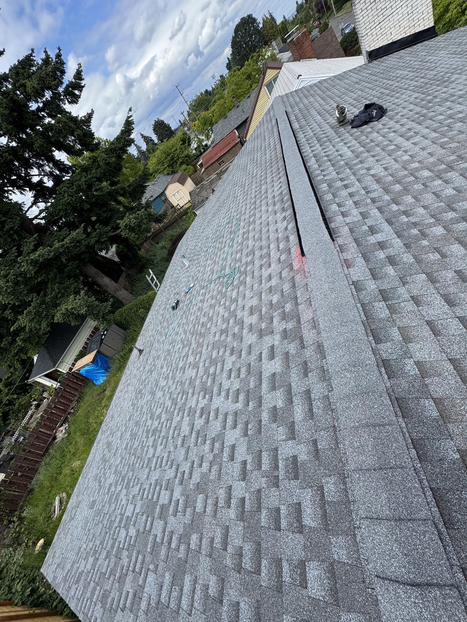 A roof with a lot of shingles on it and trees in the background.