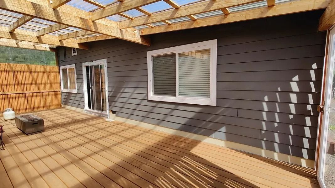 A house with a wooden deck and a pergola on top of it.