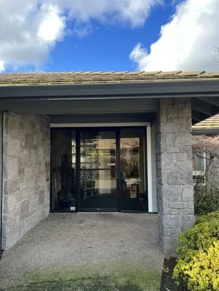 The front of a house with a large glass door and a blue sky in the background.