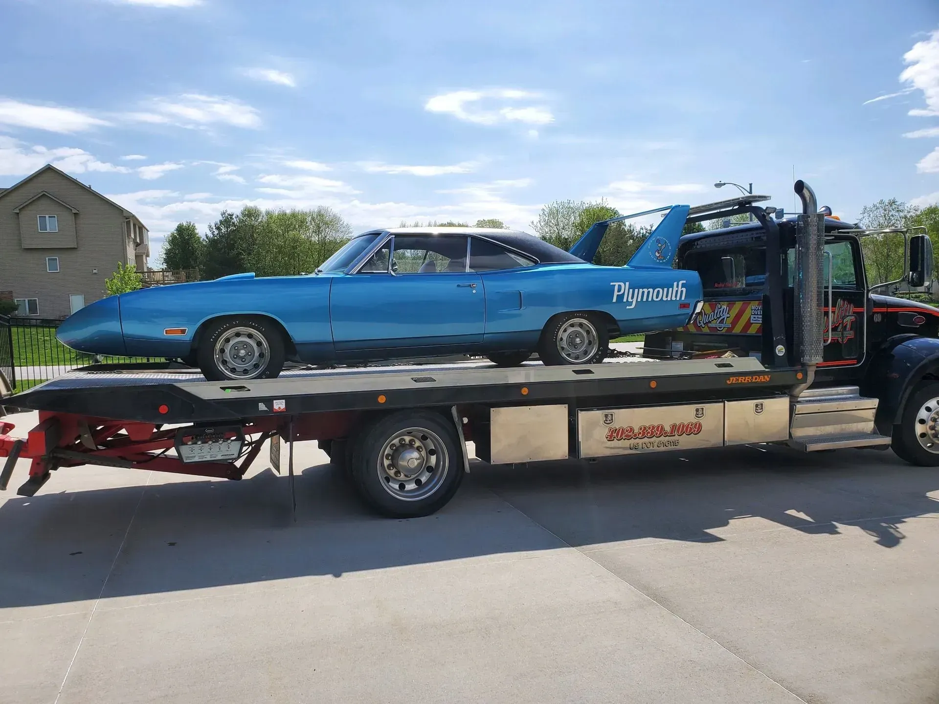 Blue classic car, Plymouth Superbird, on a flatbed tow truck.