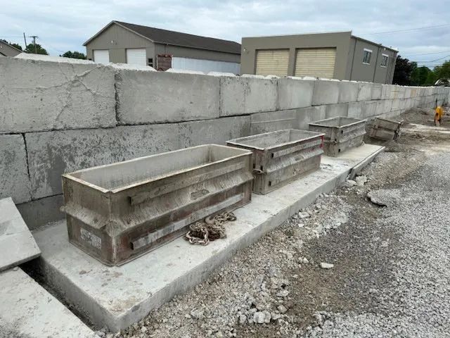 Concrete blocks forming a wall, with molds for concrete rectangular planters in front.