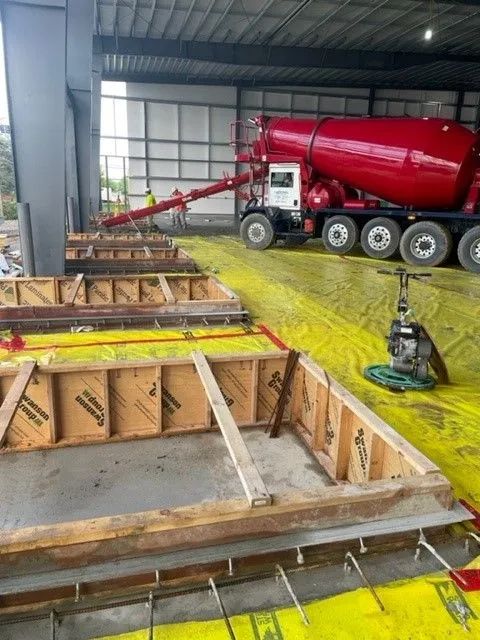 Concrete truck pouring concrete into forms on a construction site, with workers present.