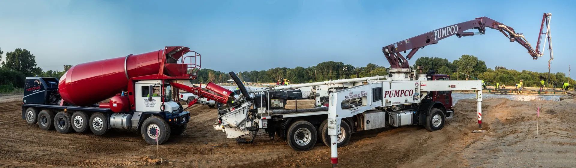 Two concrete trucks pumping concrete at a construction site.