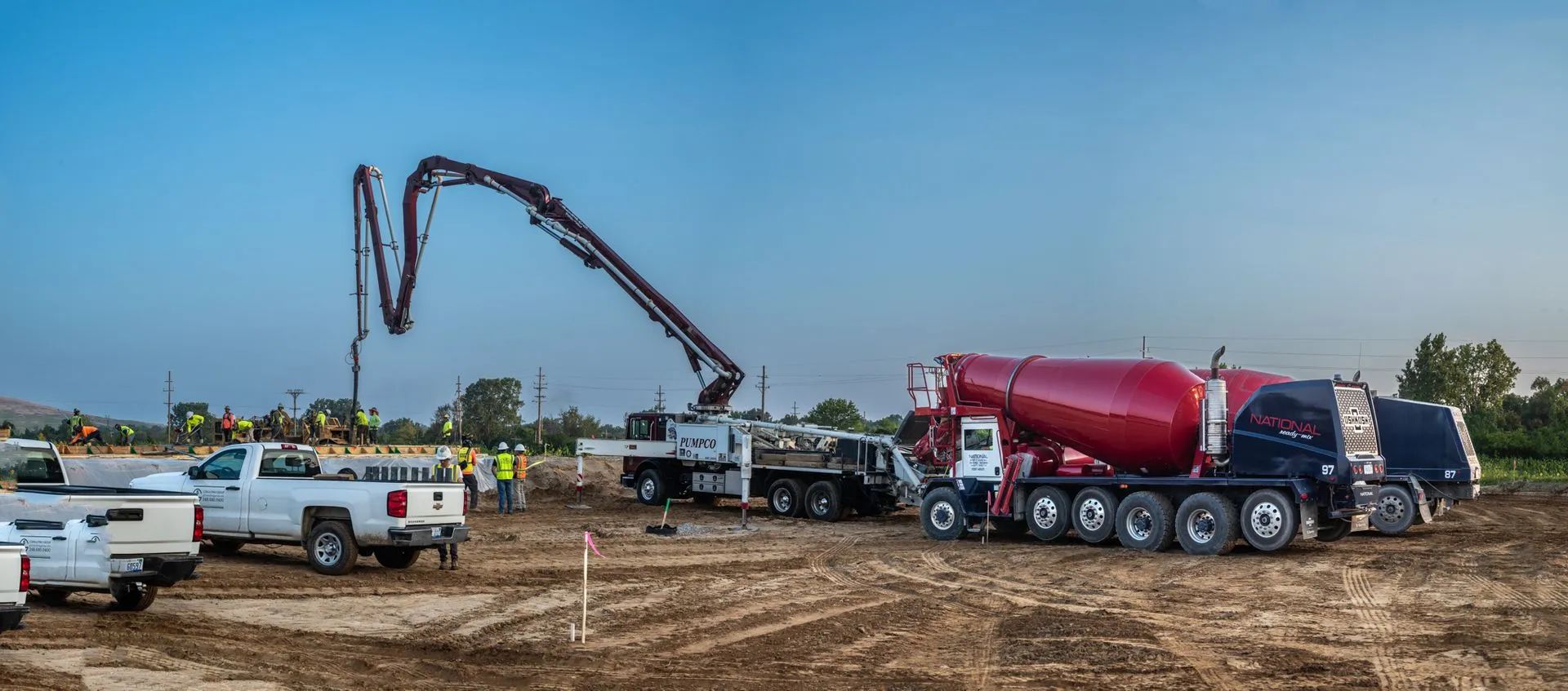 Construction site with a concrete mixer truck and a boom pump distributing concrete.