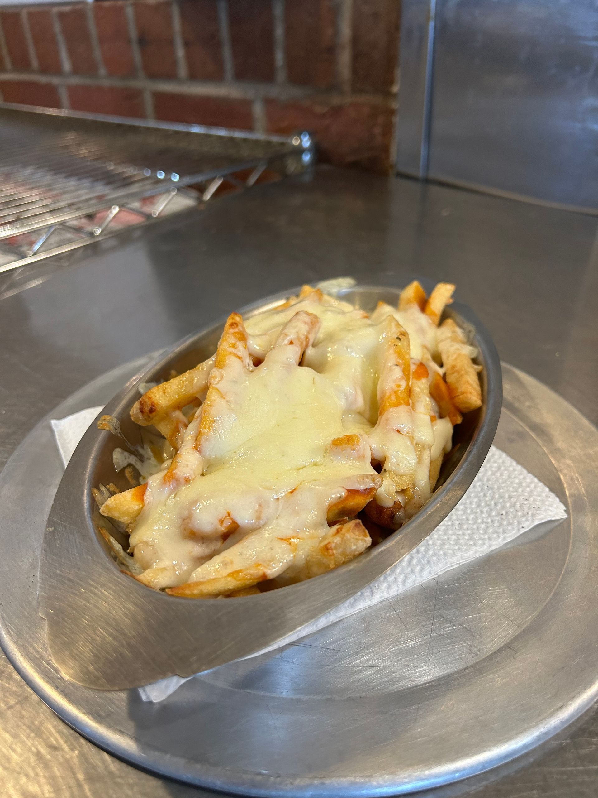 A bowl of french fries covered in cheese on a plate.
