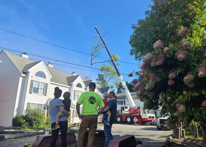 Workers and a utility truck secure a leaning utility pole on a residential street.