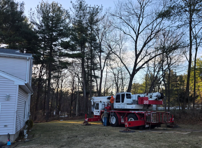 Red-and-white fire truck parked beside a house at dusk, with trees in the background.