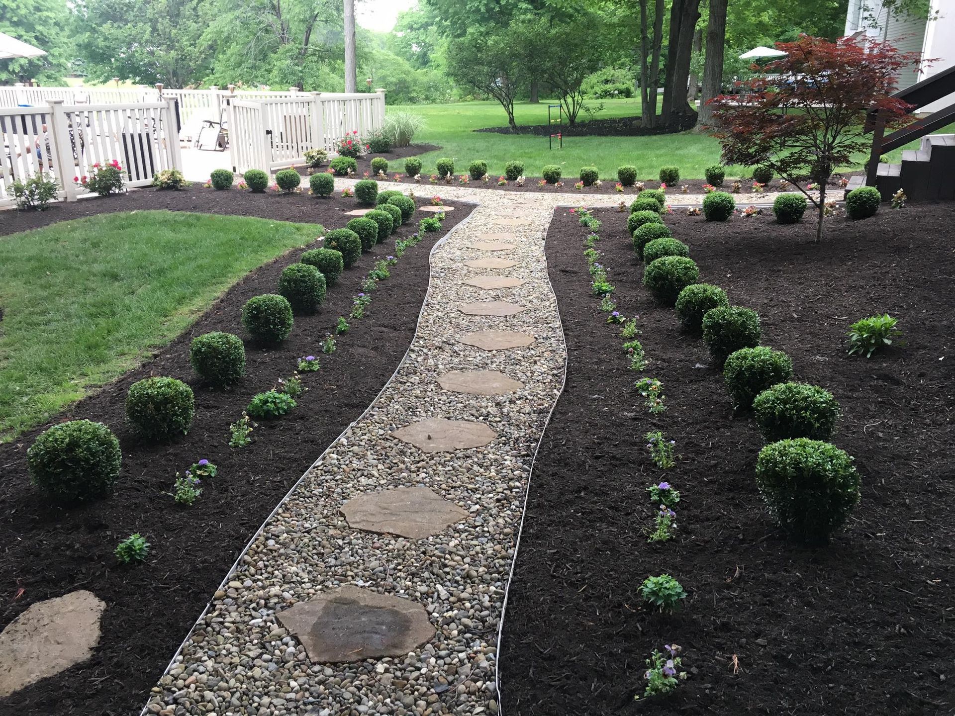 A stone walkway leading to a house in a backyard