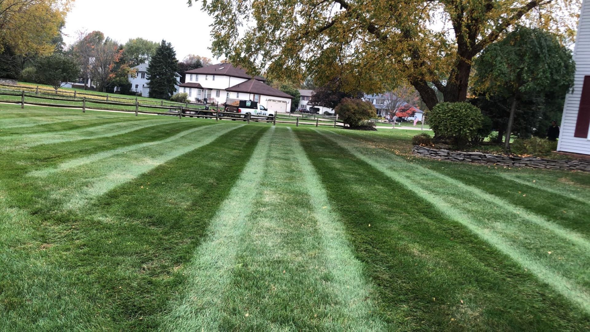 A lush green lawn with a white house in the background.