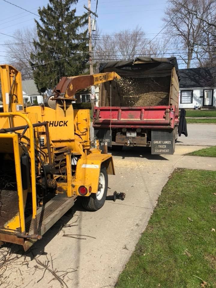 A yellow chipper and a red dump truck are parked on the side of the road.