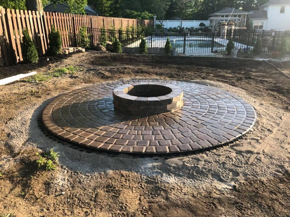 A fire pit is surrounded by bricks in a backyard.