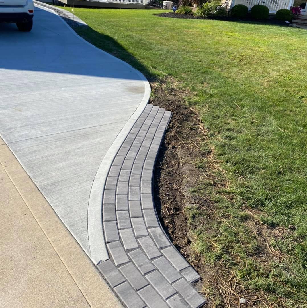 A car is parked in a driveway next to a lush green lawn.