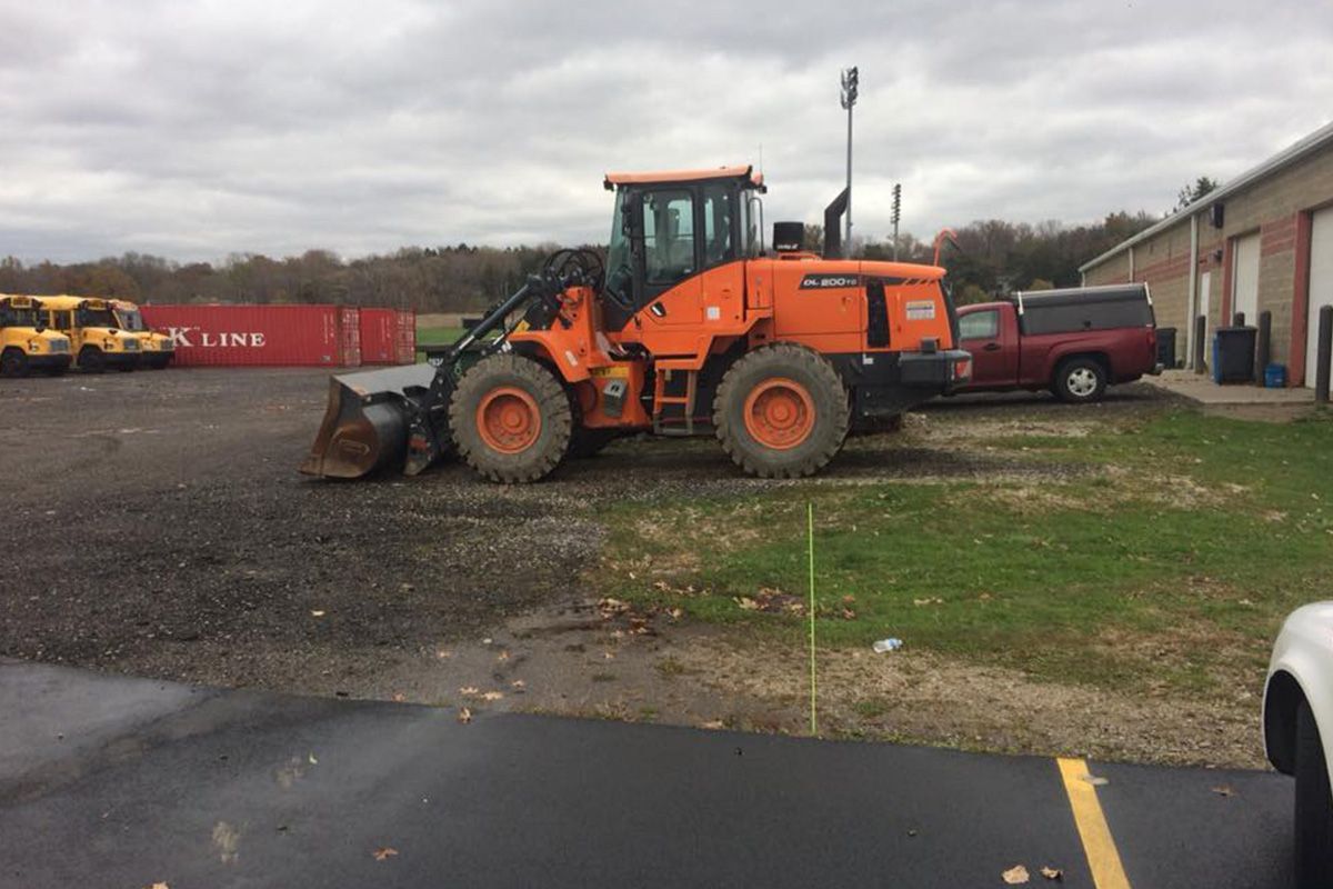 An orange bulldozer is parked in a parking lot.
