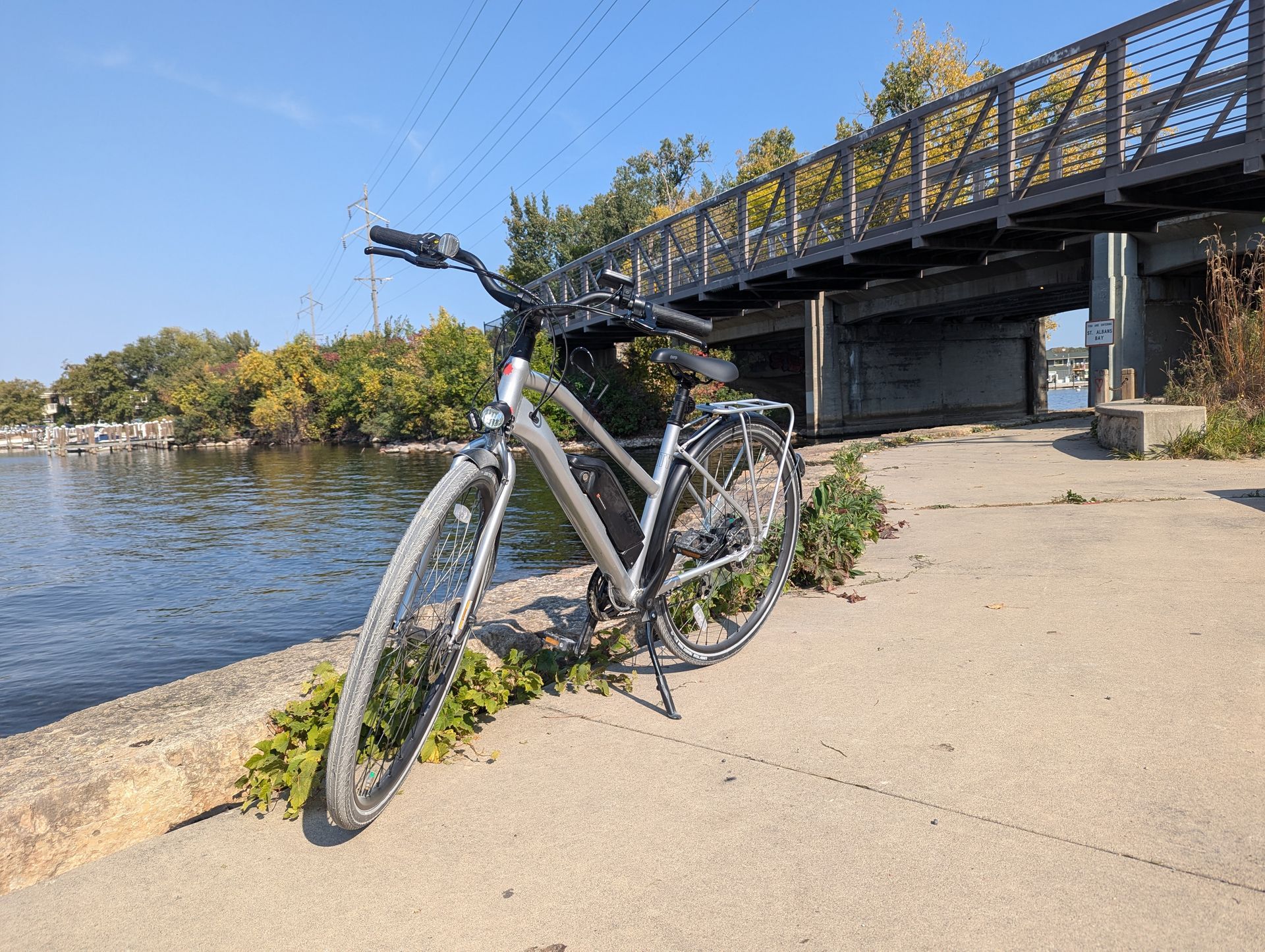 A bicycle is parked on the side of the road next to a river.