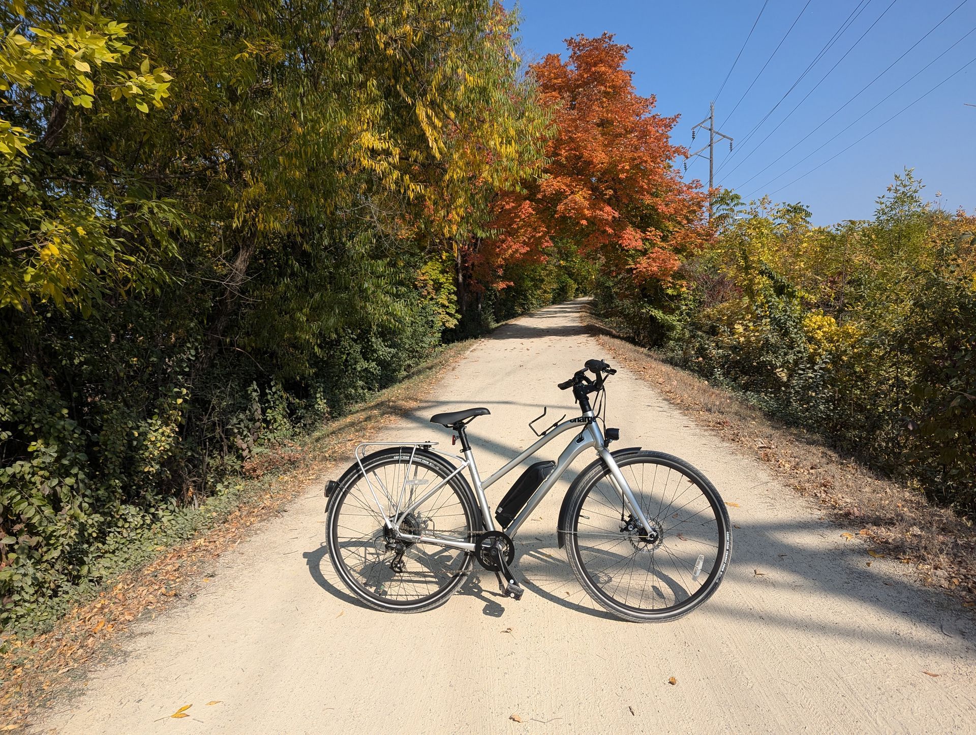A bicycle is parked on the side of a dirt road.