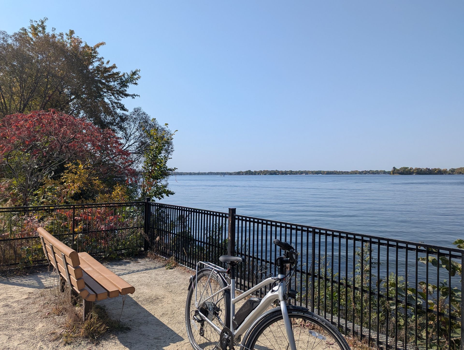 A bicycle is parked next to a bench overlooking a body of water.