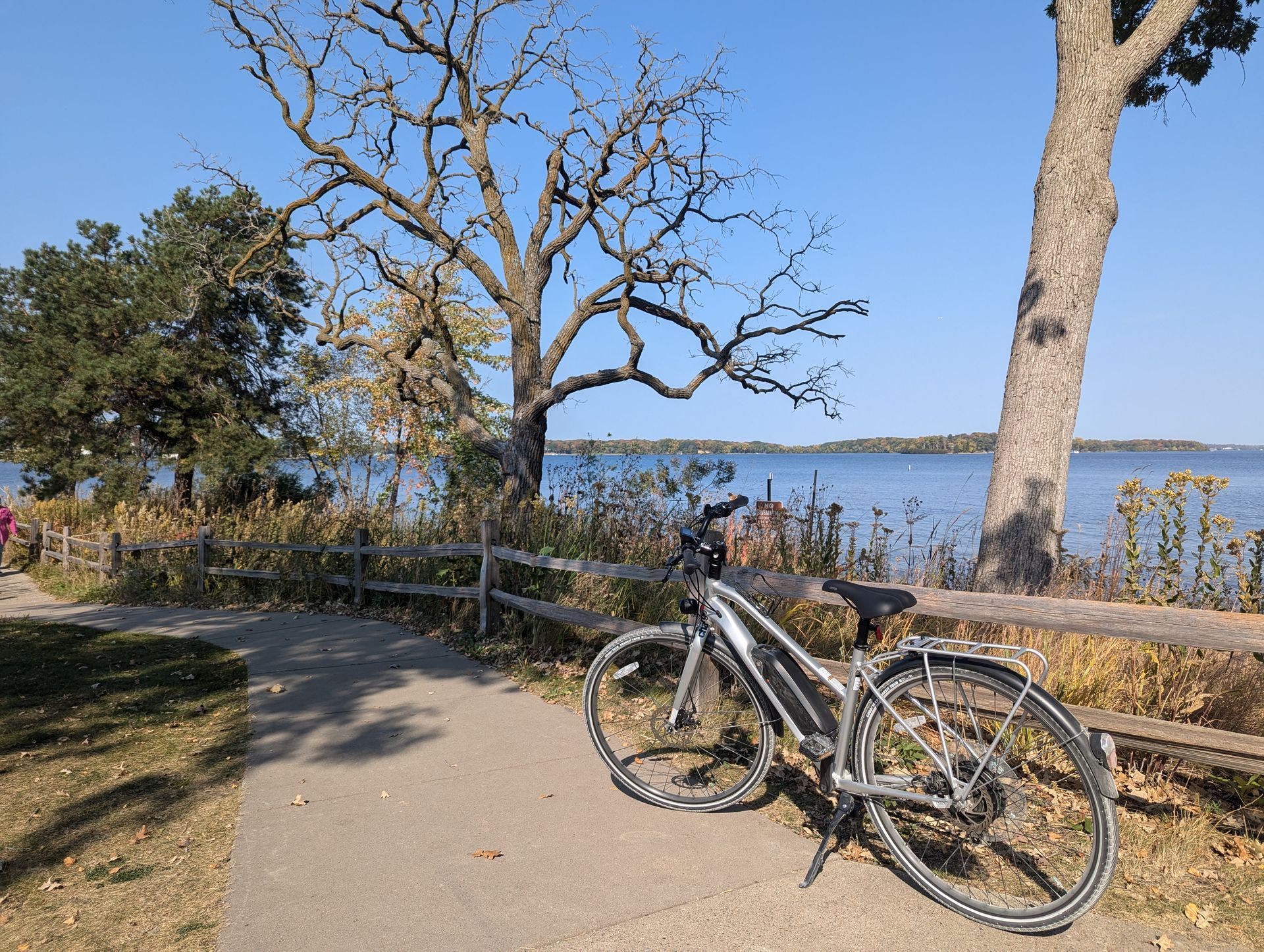 A bicycle is parked on a sidewalk next to a lake.