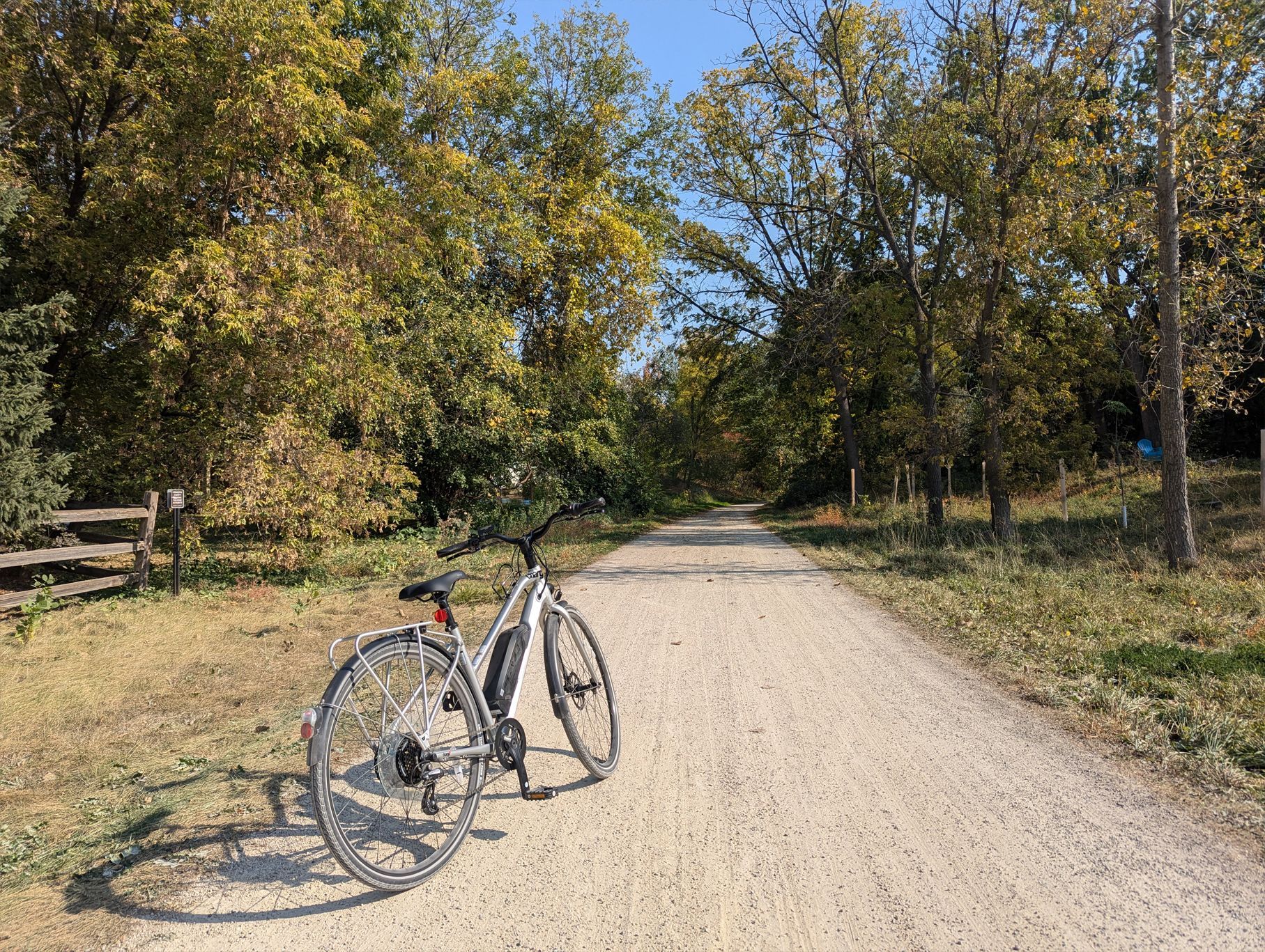 A bicycle is parked on the side of a dirt road.