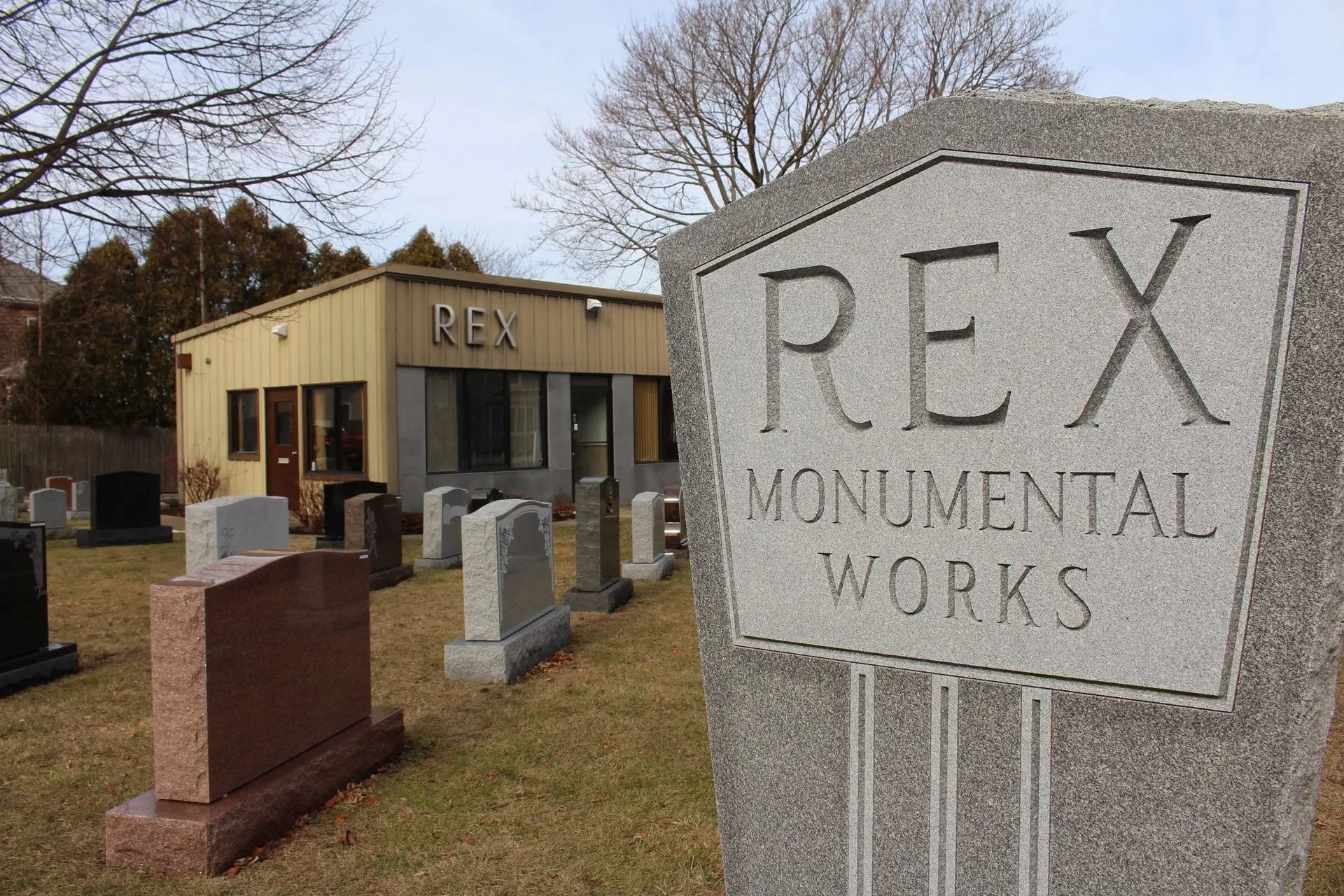 A gravestone with a sign that says Rex Monumental Works