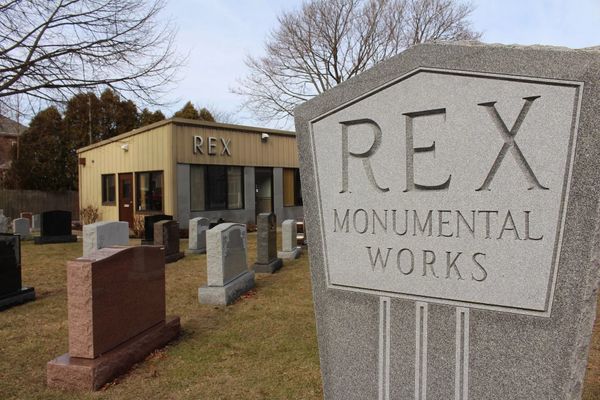 A gravestone with a sign that says Rex Monumental Works