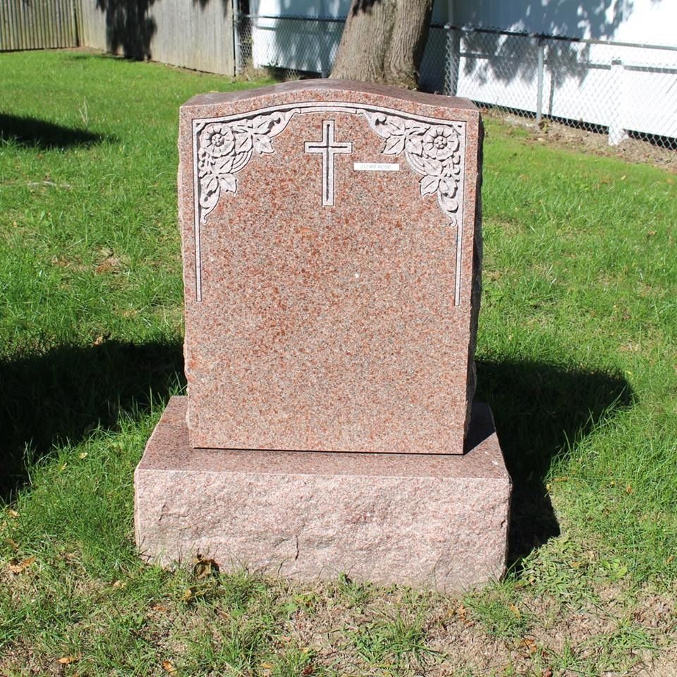 A gravestone with a cross on it in the grass