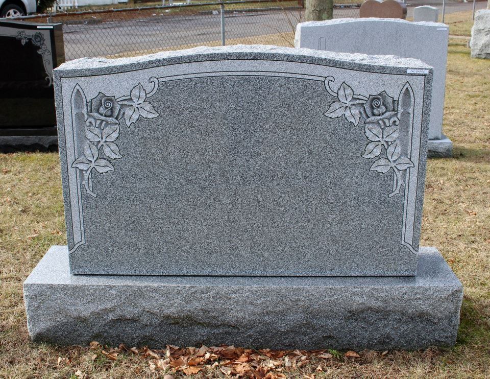A gravestone with flowers on it is in a cemetery.