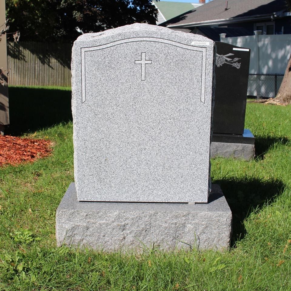 A gravestone with a cross on it in the grass
