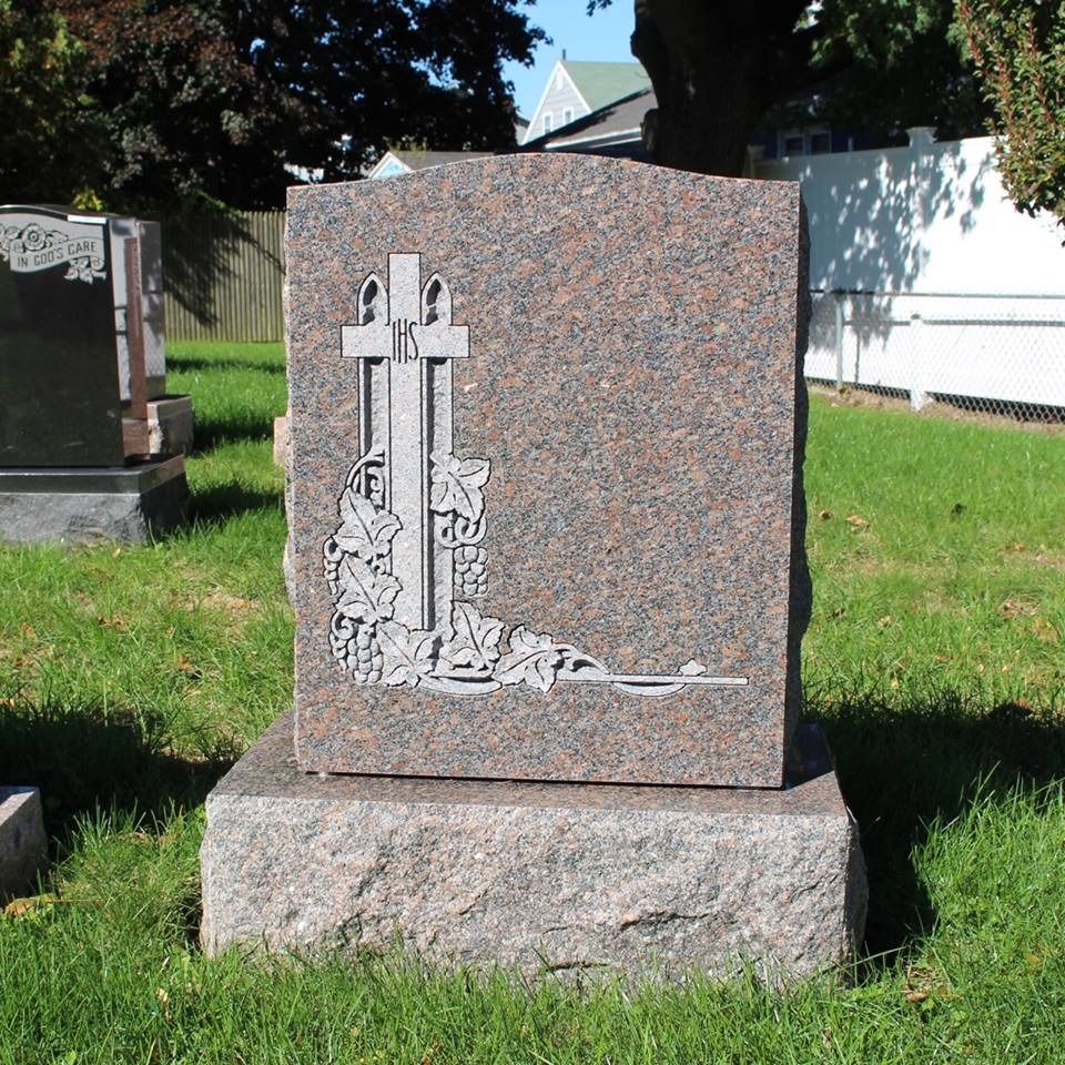 A gravestone with a cross on it in a cemetery