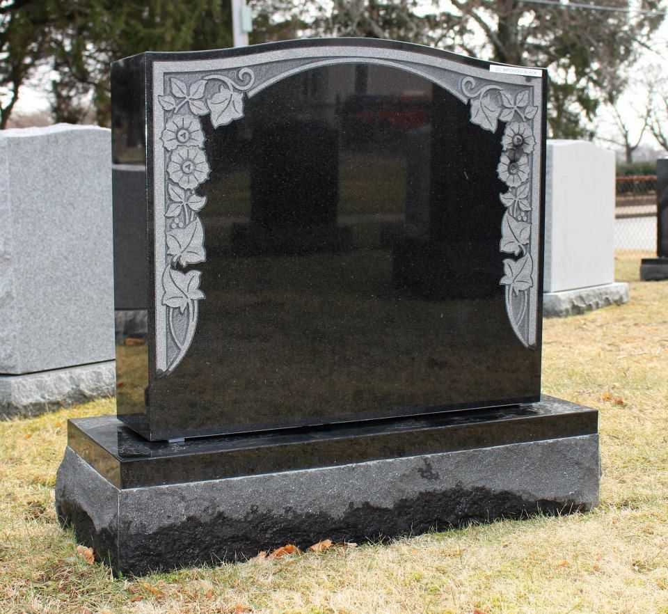 A black gravestone with a floral design on it
