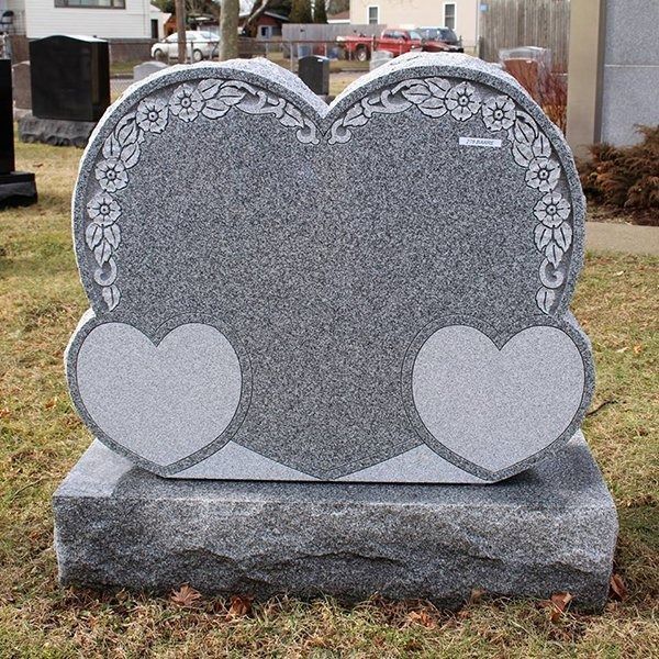 A gravestone in the shape of a heart with two hearts on it