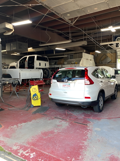 A white car is parked in a garage next to a yellow sign.