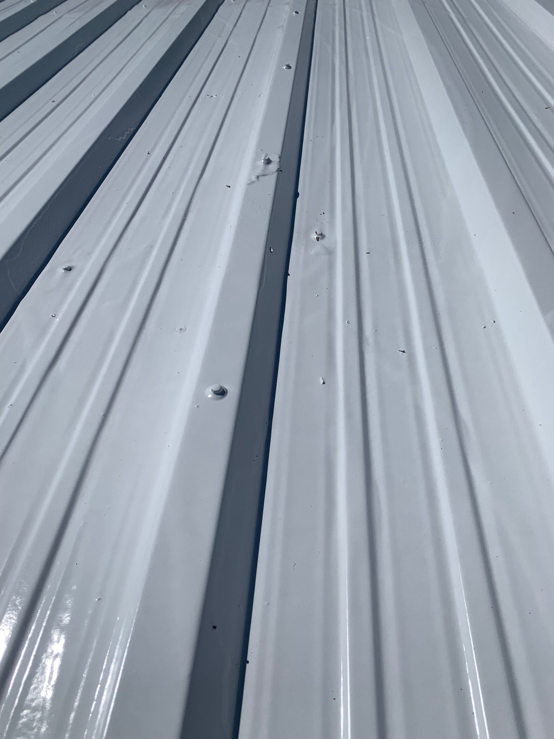 A close up of a white metal roof with black stripes.