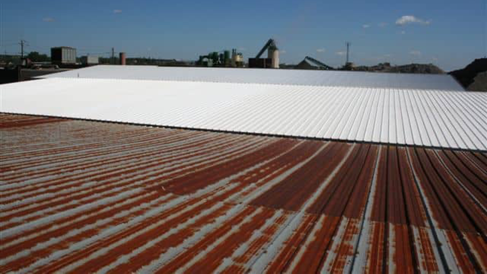 A rusty metal roof with a white roof in the background