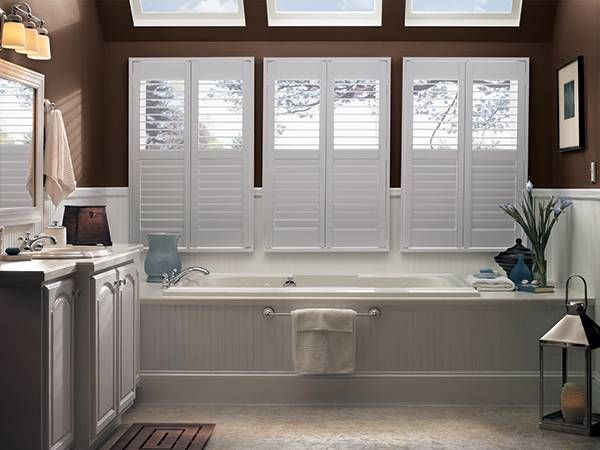 A bathroom with a tub and shutters on the windows