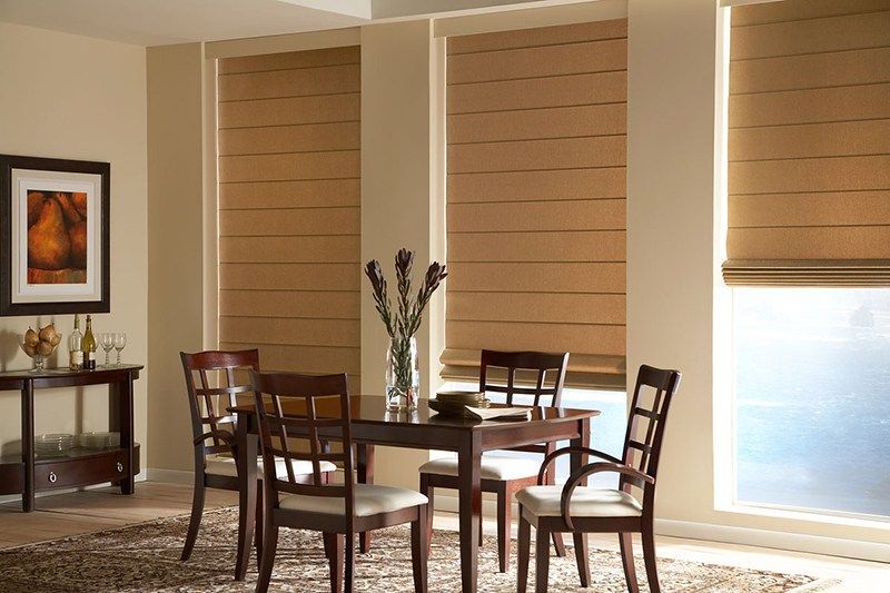 A dining room with a table and chairs and roman shades