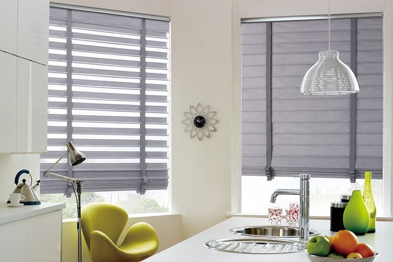 A kitchen with a sink , chair , lamp and gray blinds.