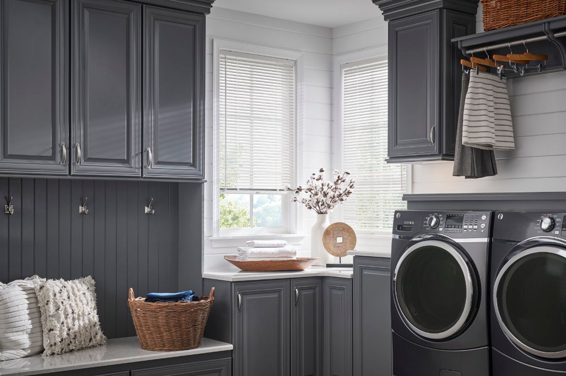 A laundry room with a washer and dryer and gray cabinets.