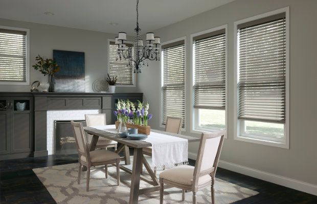 A dining room with a table and chairs and blinds on the windows.