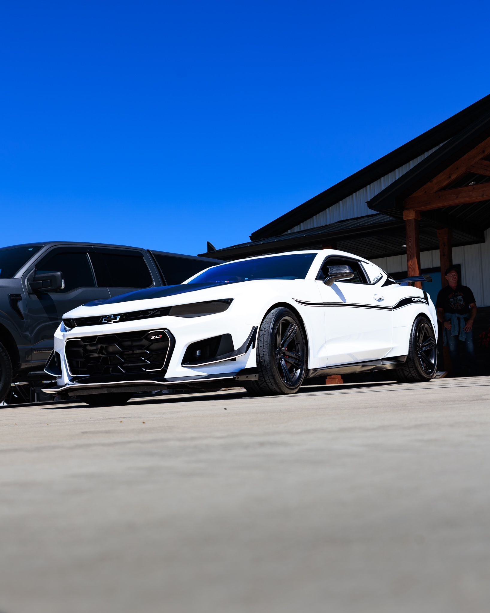 White sports car parked outside a building under a bright blue sky